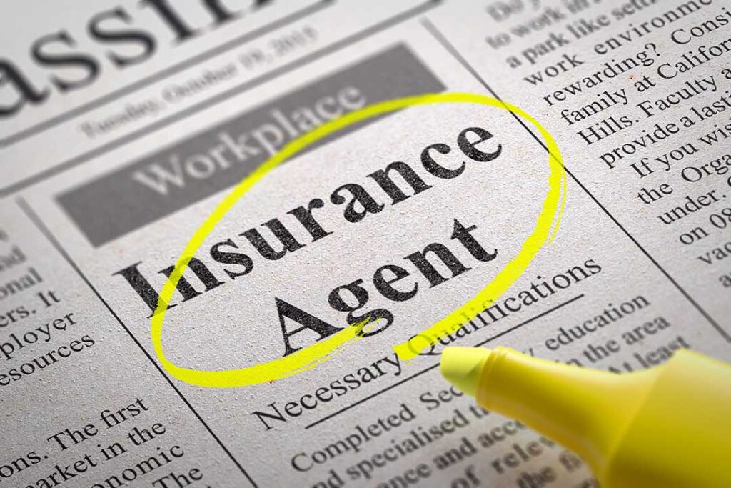 A family reviews insurance documents at a kitchen table beside a house key, car key, and umbrella.