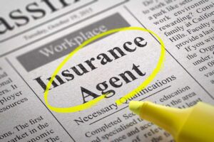 A family reviews insurance documents at a kitchen table beside a house key, car key, and umbrella.